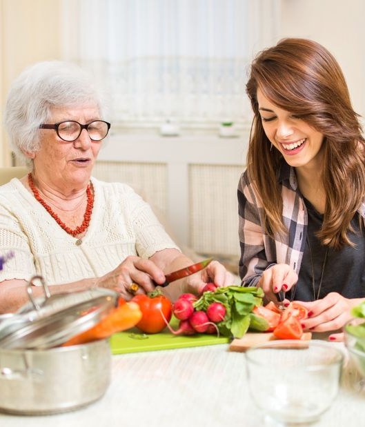 Eine Seniorin und eine junge Frau bereiten gemeinsam Gemüse zu